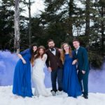 Mariés et leurs témoins dans la neige avec des fumigènes bleu