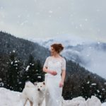 Mariée rousse à la montagne avec un chien blanc